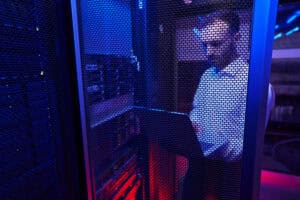 Bearded Caucasian programmer finding and troubleshooting computer server in data center