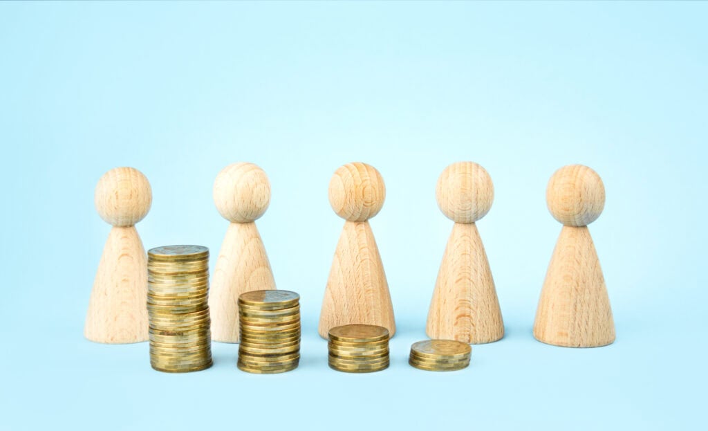 Business concept. Wooden figures of people stand around coins on a blue background. Teamwork. Earning money. Business ideas, business success. Business recovery and growth. Copy space.