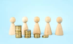 Business concept. Wooden figures of people stand around coins on a blue background. Teamwork. Earning money. Business ideas, business success. Business recovery and growth. Copy space.